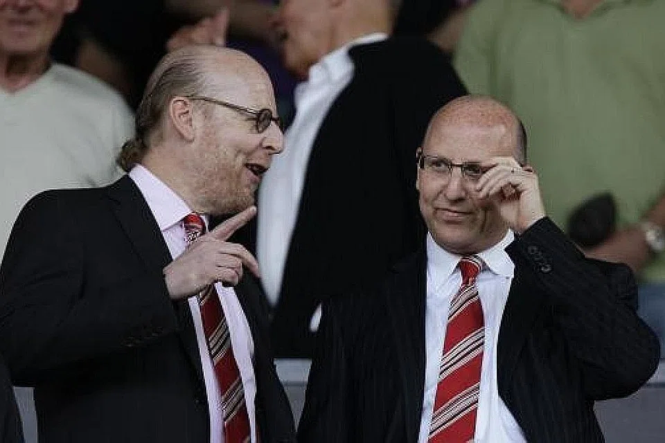 SAYANG UNITED, BENCI GLAZER: Seorang peminat Manchester United memprotes terhadap pemilik kelab itu, Joel Glazer (kanan dalam gambar atas), dengan memakai pelitup tertera ejekan 'Sayang United, Benci Glazer', dalam satu bantahan sebelum perlawanan antara kelab itu dan Liverpool Ahad lalu. Perlawanan tersebut kemudiannya terpaksa dibatalkan. - Foto Reuters, fail