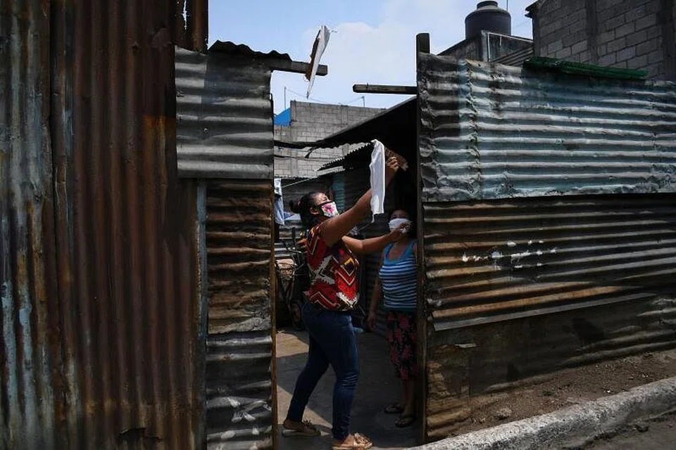 Seorang wanita menggantung bendera putih di luar rumahnya di La Brigada, Guatemala City. Menggantung bendera putih atau merah merupakan cara terdesak penduduk di sana meminta bantuan menghantar makanan atau ubat sedang pihak berkuasa mengenakan perintah berkurung. - Foto AFP