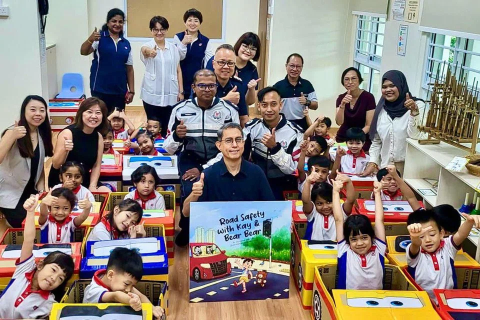 DAPAT PUJIAN: Dr Faishal (tengah, depan) sempat bergambar bersama para pegawai TP yang sama-sama membacakan buku cerita Road Safety with Kay and Bear Bear kepada kanak-kanak PCF Sparkletots.