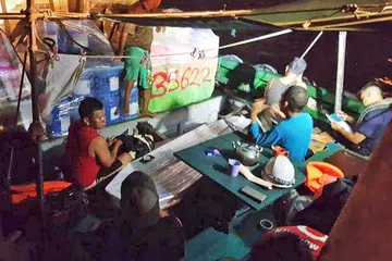 BERJAYA DISELAMATKAN: Anak kapal Samudera Indah yang berjaya diselamatkan, duduk di atas kapal Sunlight Poseidon. - Foto MOHAMED SHARJAHAN