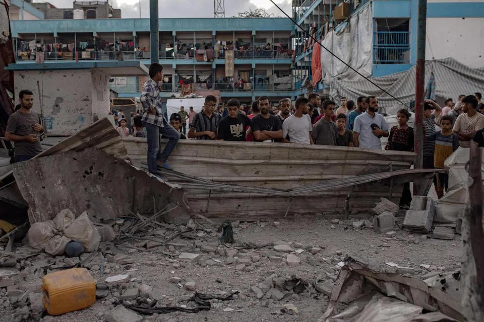 Penduduk Palestin memerhatikan kerosakan yang berlaku ekoran serangan udara Israel ke atas sekolah Al-Jawni di Nuseirat, yang dikendalikan oleh Agensi Bantuan dan Kerja Menyelamat Pertubuhan Bangsa-Bangsa Bersatu bagi Pelarian Palestin (UNRWA).