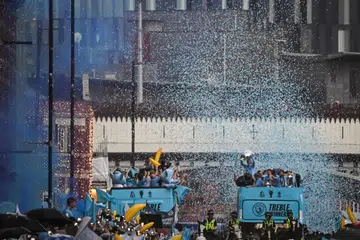BAK LAUTAN BIRU MUDA: Pemain Manchester City memperagakan tiga trofi utama yang dimenangi mereka musim ini, Liga Perdana England (EPL), Piala FA dan Liga Juara-Juara Eropah, semasa perarakan bas tanpa bumbung di kawasan utara Manchester pada Selasa. 