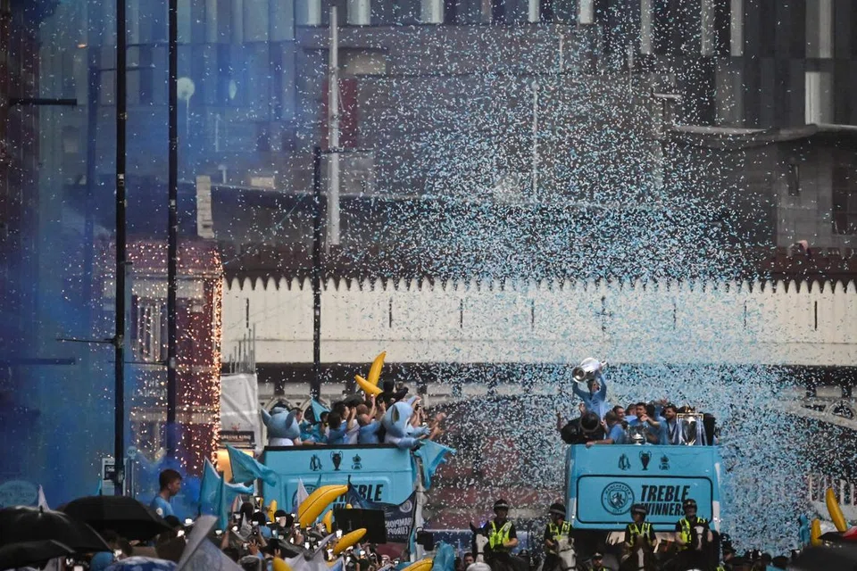 BAK LAUTAN BIRU MUDA: Pemain Manchester City memperagakan tiga trofi utama yang dimenangi mereka musim ini, Liga Perdana England (EPL), Piala FA dan Liga Juara-Juara Eropah, semasa perarakan bas tanpa bumbung di kawasan utara Manchester pada Selasa. 