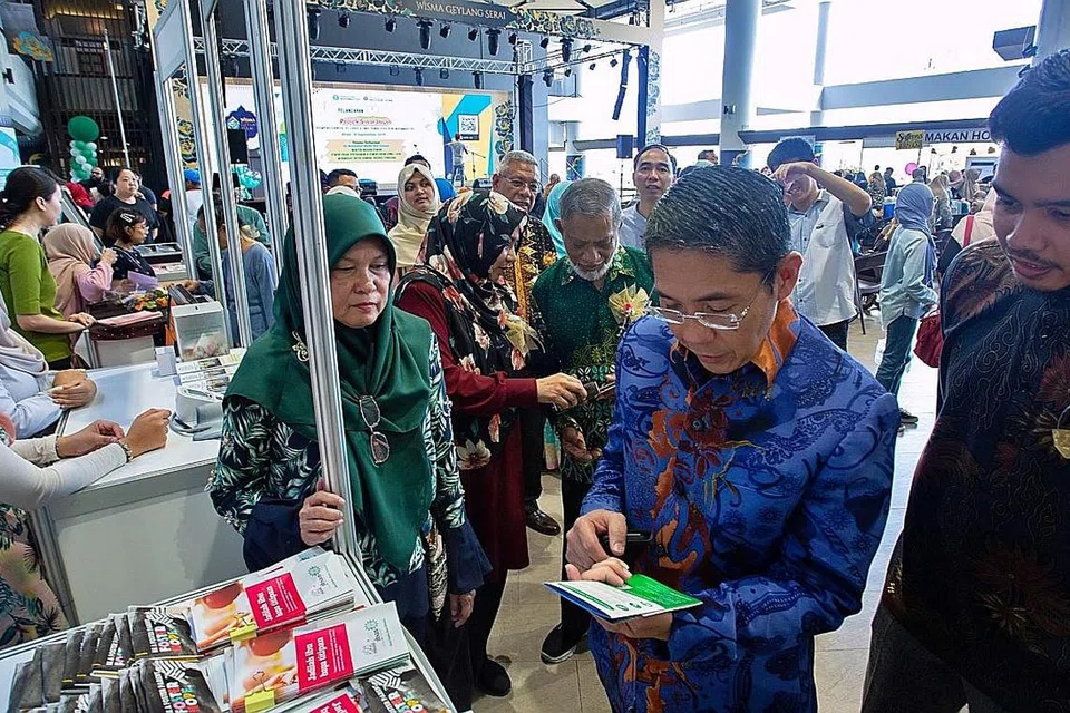 MAKLUMAT LANJUT: Dr Maliki (dua dari kanan) yang diiringi Ustaz Azri (kanan) dan mantan Presiden Muhammadiyah, Ustaz Shaik Hussain Shaik Yacob (tiga dari kanan), membaca risalah yang mengandungi maklumat tentang menjadi ibu bapa titipan yang telah disediakan oleh Muhammadiyah sewaktu majlis pelancaran semalam. - Foto BH oleh ZALEHA ABDUL KADER