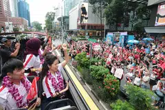 Atlet para kelihatan seperti berpesta sedang mereka tersenyum dan melambai kepada orang ramai yang berkumpul untuk menyambut kepulangan kontinjen tersebut.