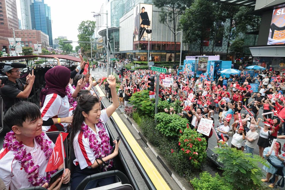 DISAMBUT SORAKAN: Atlet para menyambut sorakan dan melambai kepada orang ramai yang berkumpul untuk menyambut kepulangan kontinjen tersebut.