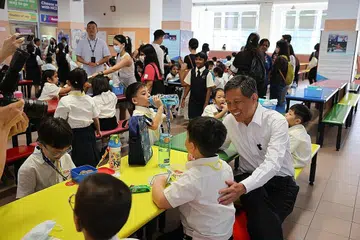 HARI PERTAMA PERSEKOLAHAN: Encik Chan (dua dari kanan) berinteraksi bersama para murid Darjah 1 semasa waktu rehat mereka di Sekolah Rendah Ang Mo Kio pagi semalam. - Foto BH oleh ONG WEE JIN