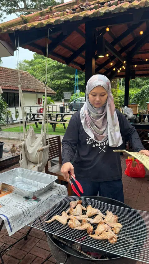 Penulis membakar ayam di pit barbeku.