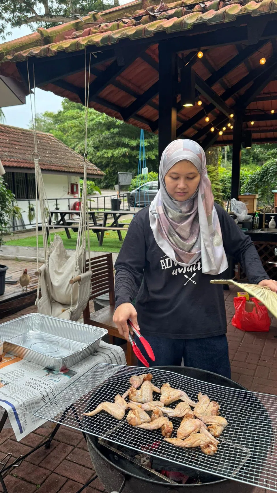 Penulis membakar ayam di pit barbeku.