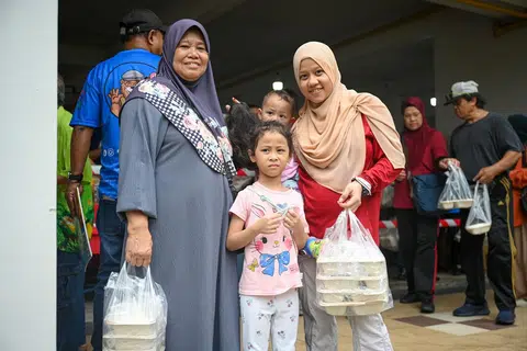 BERIANI PERCUMA: Cik Hanipah, 66 tahun (paling kiri) bersama anaknya Cik Azizah Chomil (berpakaian merah putih), 33 tahun dan dua cucunya Alisha Syed Shafiq, 5 tahun (tengah berdiri) serta Nawal Syed Shafiq, 1 tahun (didukung) hadir di Bedok North untuk mendapatkan beriani percuma dari Free Food For All.