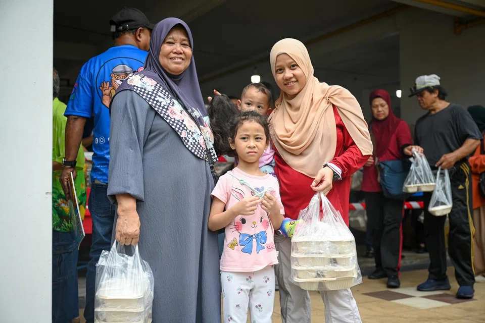 BERIANI PERCUMA: Cik Hanipah, 66 tahun (paling kiri) bersama anaknya Cik Azizah Chomil (berpakaian merah putih), 33 tahun dan dua cucunya Alisha Syed Shafiq, 5 tahun (tengah berdiri) serta Nawal Syed Shafiq, 1 tahun (didukung) hadir di Bedok North untuk mendapatkan beriani percuma dari Free Food For All.