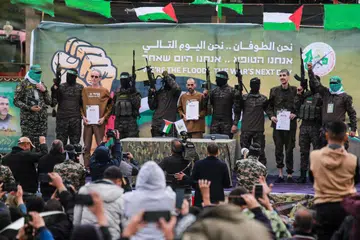 Kumpulan Hamas mengiringi tebusan Israel (dari kiri, memegang sijil) Ohad Ben Ami, Or Levy, dan Eli Sharabi, di atas pentas sebelum menyerahkan mereka kepada pasukan Palang Merah di Deir el-Balah, tengah Gaza, pada 8 Februari.