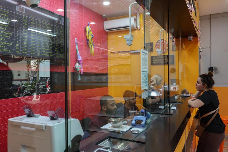 Seorang pekerja pengurup wang membantu pelanggan tentang maklumat terkini mata wang asing di sebuah kedai pengurup wang berlesen di Kuala Lumpur.