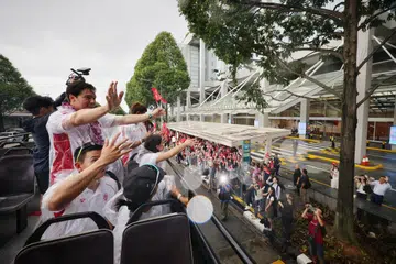 Meskipun cuaca mendung dan hujan, ia tidak memadamkan semangat atlet luncur lelayang Maximilian Maeder (dua dari depan, berdiri) dan rakan-rakan Olympiknya yang lain untuk menyambut dan melambai kepada penyokong di perhentian bas di Marina Bay Sands pada 14 Ogos.