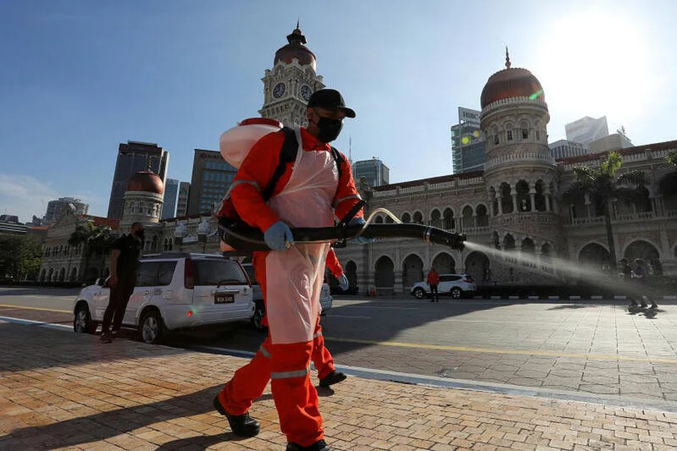 LANGKAH BERJAGA-JAGA: Seorang pekerja di Kuala Lumpur melakukan penyahjangkitan dalam keadaan Malaysia masih lagi bertarung dengan jumlah kes baru koronavirus yang tinggi. - Foto REUTERS