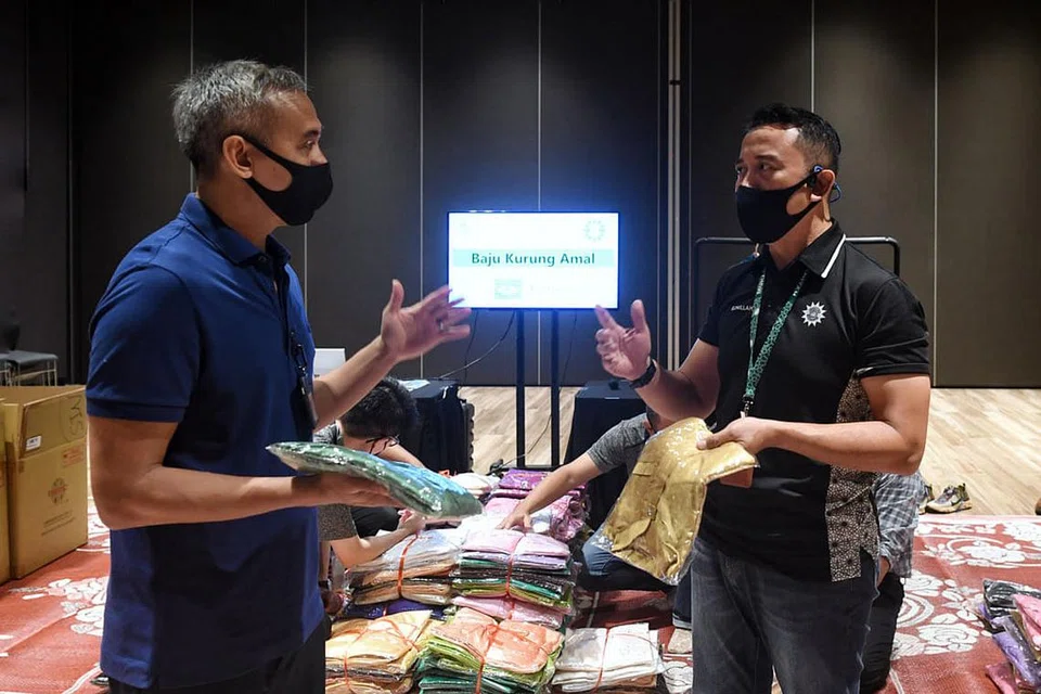 MENYINGSING LENGAN: Pengurus Besar Wisma Geylang Serai, Encik Nur Effendi Esa (kiri), dan Pengurus Unit Komunikasi Korporat dan Sumber Persatuan Muhammadiyah, Encik Mohamad Eznillah Razali (kanan), turut menghulurkan tenaga dalam projek amal #bajukurungamal yang dijalankan Kurnia@WGS.