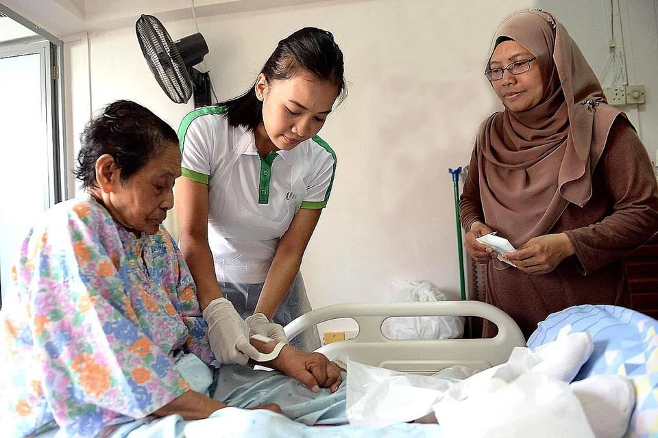 SELESA DENGAN MISI: Jururawat Berdaftar Kanan Siti Norbaya (tengah) menukar pembalut luka Cik Sameah Nahuwam, 85 tahun, sambil diperhatikan anak bongsu Cik Sameah, Cik Rohani Abu Bakri, 43 tahun. Cik Siti Norbaya turut mengajar cara menukar pembalut luka kepada penjaga pesakitnya agar mereka juga boleh melakukan hal tersebut jika perlu. - Foto KHALID BABA