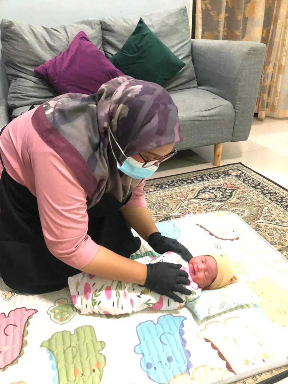 Seorang penjaga ibu berpantang sedang mengurus bayi.