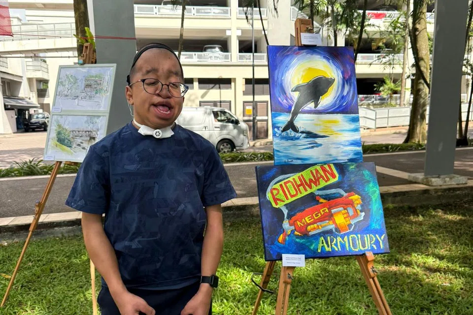 SUARA SENI: Muhammad Ridhwan Masli, 19 tahun, bersama salah satu hasil lukisannya yang dipamerkan di Pameran Seni Masyarakat SG60 di Tasik Guilin, Bukit Gombak pada 10 Ogos, sempena ulang tahun kemerdekaan ke-60 Singapura. 