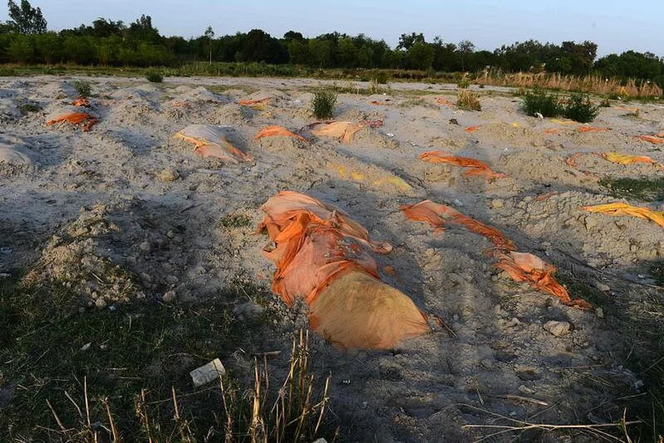 TERBIAR BEGITU SAHAJA: Tubuh manusia yang disyaki mangsa Covid-19 ditanam dalam kawasan perkuburan cetek di tebing sungai Ganges di Rautapur Ganga Ghat di Unnao. - Foto SANJAY KANOJIA / AFP 