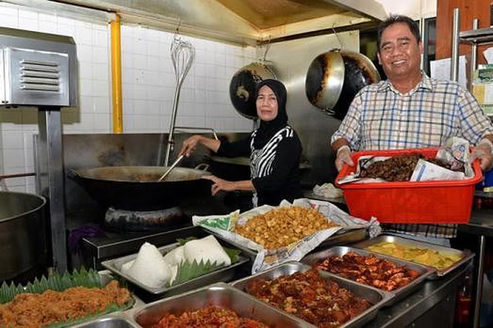 TARIKAN LAUK RAYA BAGI TAMU BUKAN MELAYU: Encik Zainuddin Sajat, pemilik Aspirasi Food Galore, berkata masih ramai pelanggan menempah lauk Raya bagi rumah terbuka mereka, terutama sekali untuk dihidangkan kepada teman sekerja atau sekolah yang berlainan bangsa. Gambar menunjukkan beliau dan salah seorang karyawannya, Cik Shila Sukardi, di kilang tempat mereka menyediakan makanan. - Foto MO.SALLEH
