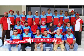 SOKONGAN PADU: Encik Akbar Hashim (kiri, bertopi dan berbaju merah putih) bergambar bersama anggota kelab penyokong Die Hard Fans Singapura semasa melancarkan jersi yang akan mereka gunakan bagi perlawanan Piala AFF Suzuki kali ini. - Foto SHAFIE GOH