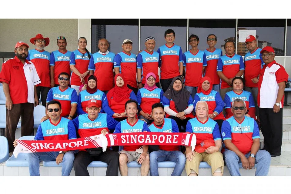 SOKONGAN PADU: Encik Akbar Hashim (kiri, bertopi dan berbaju merah putih) bergambar bersama anggota kelab penyokong Die Hard Fans Singapura semasa melancarkan jersi yang akan mereka gunakan bagi perlawanan Piala AFF Suzuki kali ini. - Foto SHAFIE GOH