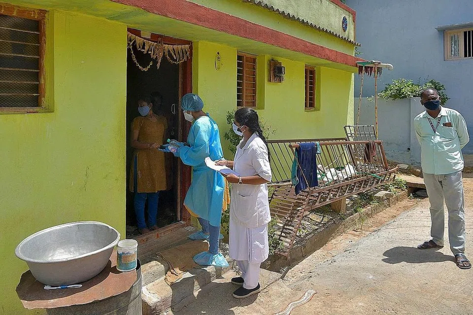 DEKATI PENDUDUK: Pekerja Kesihatan melakukan kunjungan rumah-ke-rumah untuk melakukan ujian bagi mengesan virus Covid-19 di kawasan luar bandar Bangalore, India. Varian virus Covid-19 Delta kali pertama dikesan di negara itu. - Foto AFP