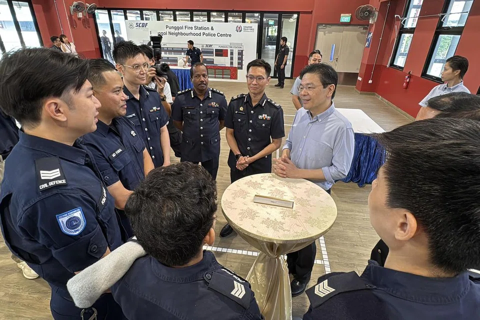 Perdana Menteri Lawrence Wong (berkemeja biru air) beramah-tamah bersama para pegawai SPF dan SCDF semasa melawat Pusat Polis Kejiranan Punggol dan Balai Bomba Punggol pada 4 April. 