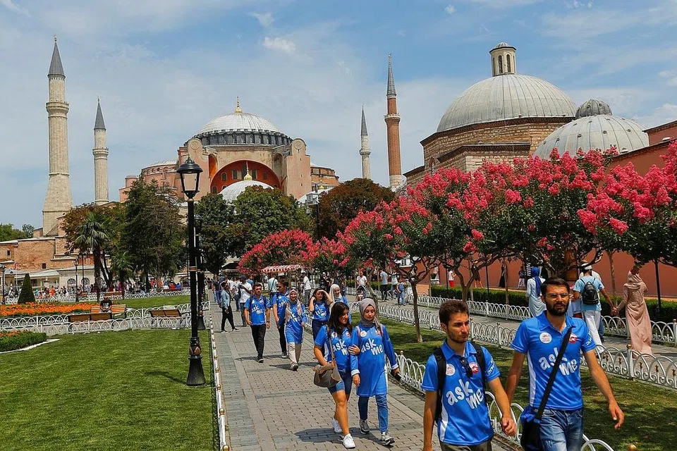 PELANCONGAN MUSLIM BERKEMBANG: Sekumpulan pemandu pelancong sukarela di bandar lama Istanbul, Turkey, berlatarbelakangkan bangunan zaman silam Hagia Sophia. - Foto REUTERS