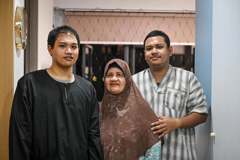 Cik Rasima Yunos (tengah) bersama anak sulungnya, Encik Ridzwansah Jumangin (kanan), dan anak bongsunya, Encik Muszafarsyah Jumangin, di rumah baru mereka di flat HDB dua bilik di Sengkang. 