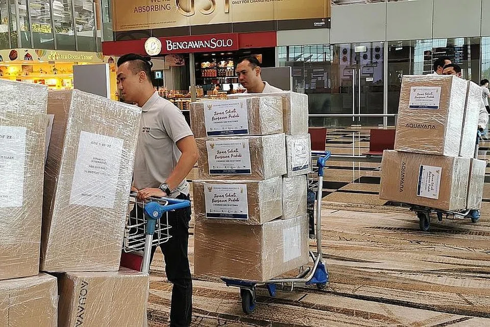 KIRIM BANTUAN: Sukarelawan Humanity Matters kelihatan menyorong bekalan bantuan ke Lapangan Terbang Changi untuk dikirimkan ke Indonesia. - Foto HUMANITY MATTERS