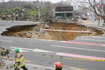 Petugas penyelamat berjalan melepasi sebuah lubang benam besar yang terbentuk di hadapan sebuah kedai tanaman di tepi jalan di Seoul pada 25 Mac 2025. Seorang lelaki disahkan maut selepas motosikalnya  ditelan oleh lubang tersebut, menurut Jabatan Bomba. Insiden ngeri itu dirakam dalam rakaman video yang menunjukkan detik kenderaan mangsa terjatuh ke dalam lubang secara tiba-tiba. Lubang berkenaan muncul secara mendadak di sebuah persimpangan sibuk di tenggara ibu kota Korea Selatan sekitar jam 6:30 petang waktu tempatan pada 24 Mac. 
