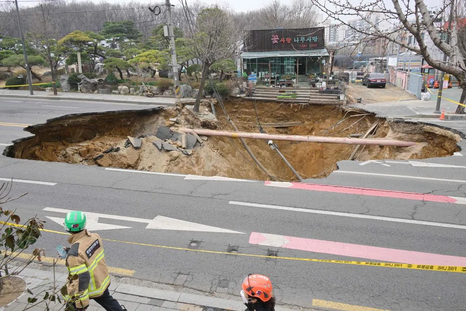 Petugas penyelamat berjalan melepasi sebuah lubang benam besar yang terbentuk di hadapan sebuah kedai tanaman di tepi jalan di Seoul pada 25 Mac 2025. Seorang lelaki disahkan maut selepas motosikalnya  ditelan oleh lubang tersebut, menurut Jabatan Bomba. Insiden ngeri itu dirakam dalam rakaman video yang menunjukkan detik kenderaan mangsa terjatuh ke dalam lubang secara tiba-tiba. Lubang berkenaan muncul secara mendadak di sebuah persimpangan sibuk di tenggara ibu kota Korea Selatan sekitar jam 6:30 petang waktu tempatan pada 24 Mac. 