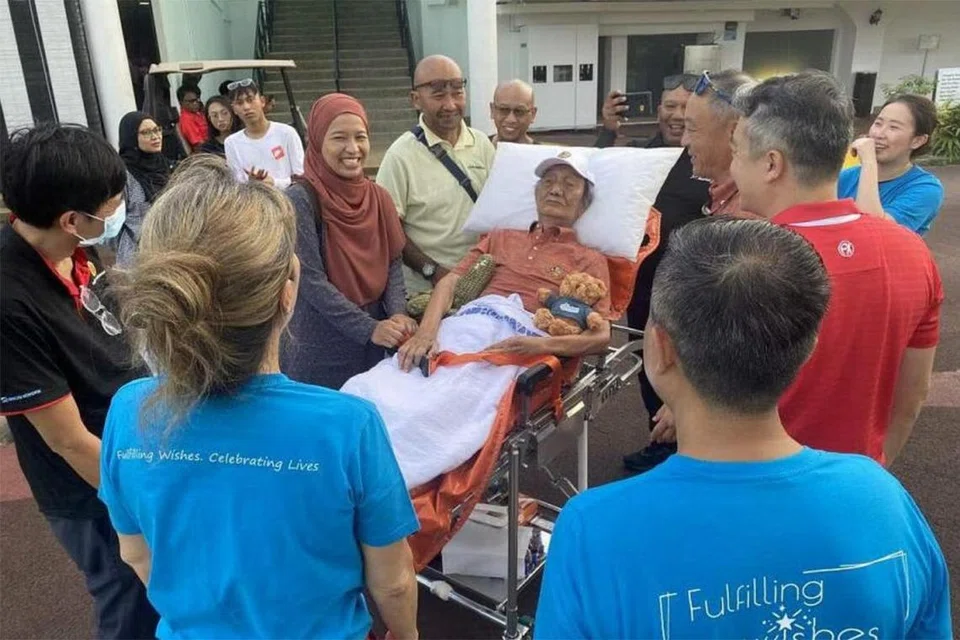 HASRAT DIPENUHI: Encik Mohd Salleh Ismail yang pernah bekerja sebagai kedi, dikelilingi ahli keluarga dan sukarelawan AWS semasa lawatannya ke Singapore Island Country Club pada 7 Mei. 