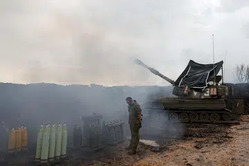 Seorang askar Israel berdiri di samping unit artileri mudah alih di sempadan Israel-Lebanon di utara Israel.