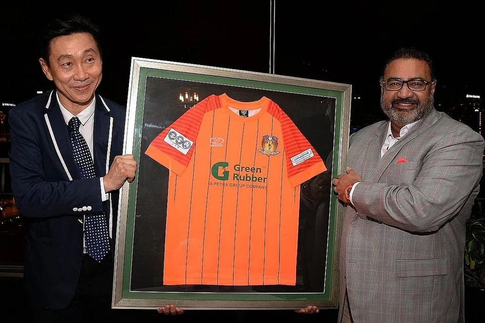 KERJASAMA MEMBAWA PEMBAHARUAN: Pengerusi Hougang United, Encik Bill Ng (kiri), menyampaikan kit terbaru kelab itu kepada pengerusi dan pengasas Green Rubber Global, Encik Vinod Sekhar, salah satu penaja utama kelab itu. - Foto ZAINAL YAHYA
