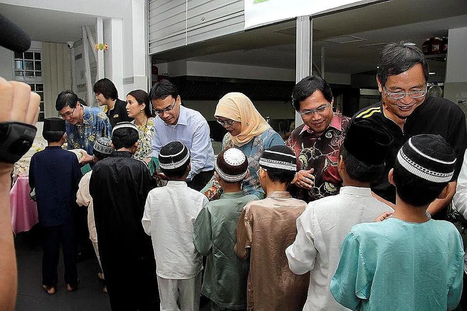 SESI IFTAR: Pada 31 Julai 2013, para eksekutif dari Maybank Singapura menghulurkan sumbangan dan beg habuan kepada anak yatim Darul Ma'wa semasa sesi berbuka puasa. - Foto fail