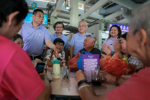 Setiausaha Agung Parti Kuasa Rakyat (PPP) Encik Goh Meng Seng (berdiri, tiga dari kiri), dan Encik Peter Soh (kiri), bersama pasukan PPP mendekati penduduk pada 12 April di Pasar Bulat Tampines di Tampines Street 11. 
