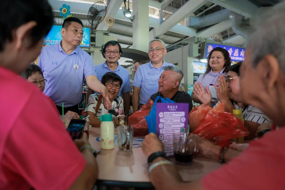 Setiausaha Agung Parti Kuasa Rakyat (PPP) Encik Goh Meng Seng (berdiri, tiga dari kiri), dan Encik Peter Soh (kiri), bersama pasukan PPP mendekati penduduk pada 12 April di Pasar Bulat Tampines di Tampines Street 11. 