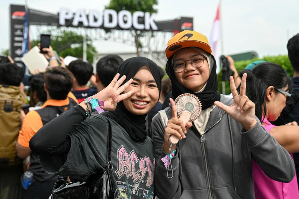 Peminat pasukan McLaren dari Indonesia, Queisha Syareefa Kamil (kanan) dan Alya Hafiza, kedua-duanya pelajar berusia 15 tahun, menantikan kelibat pemandu kegemaran mereka di luar Bangunan Pit F1. 
