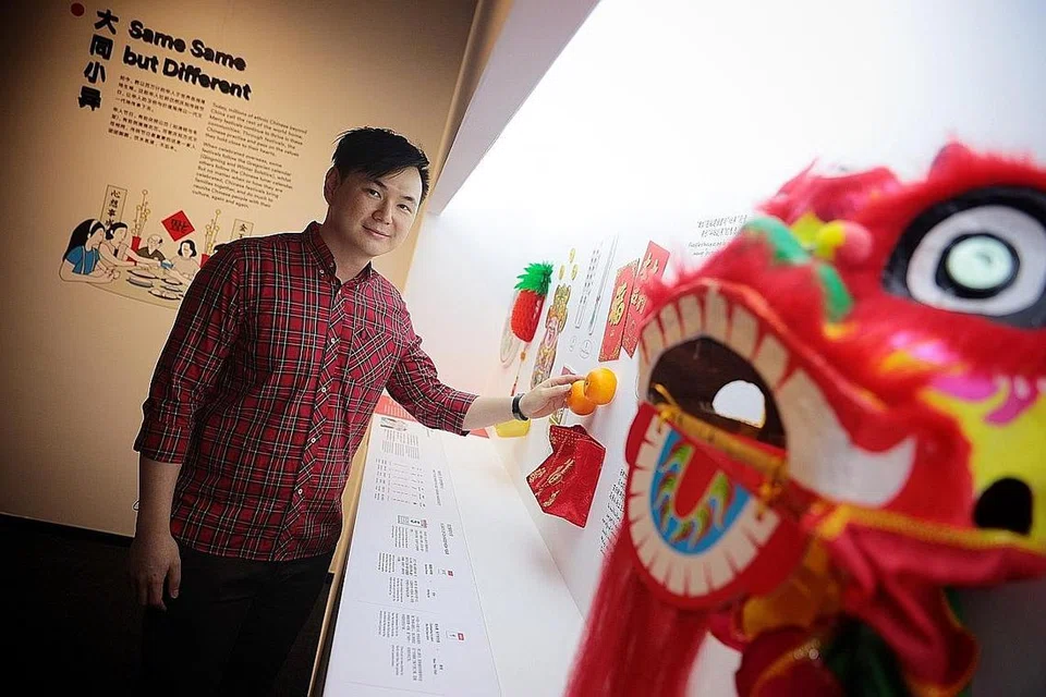 TRADISI CINA: Encik Shaun Choh mengenakan pakaian merah sambil memegang buah limau Mandarin yang biasanya dihadiahkan sewaktu Tahun Baru Cina. Beliau bergambar berdekatan patung singa yang digunakan sewaktu tarian singa semasa perayaan tahun baru. - Foto BH oleh JASON QUAH