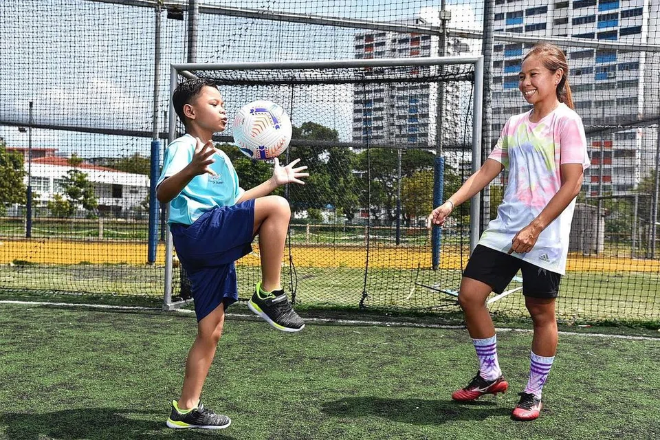 MAHU ASAH POTENSI PELAJAR AUTISME: Cik Ernie (kanan) mengajar seorang pelajar Singa Champs, Muhamad Ruzaiman Muhamad Rosli, sembilan tahun, cara untuk menimbang bola. - Foto BH oleh DESMOND WEE dan FACEBOOK ERNIE SONTARIL