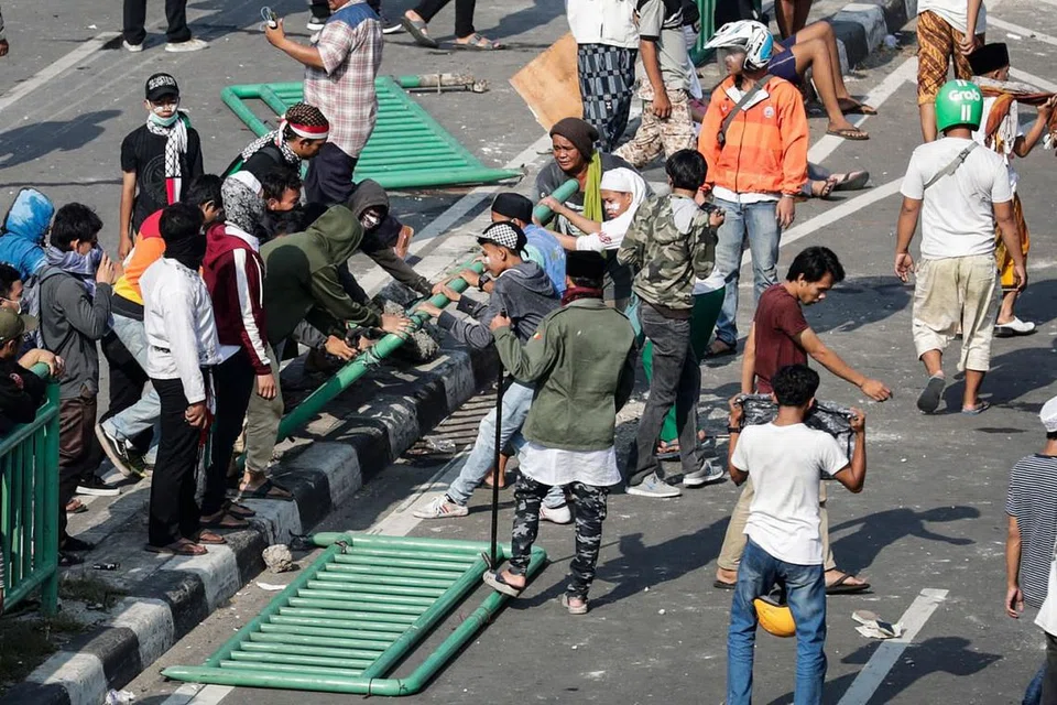 MUSNAHKAN HARTA BENDA AWAM: Perusuh memecah serta menanggalkan besi pembahagi jalan tatkala mereka bertempur dengan pegawai polis. - Foto EPA-EFE