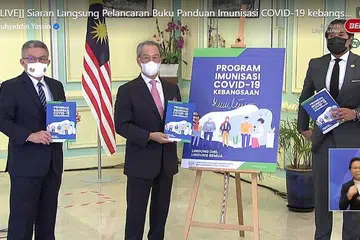 BUKU PANDUAN VAKSIN COVID-19: Tan Sri Muhyiddin Yassin, diapit Menteri Kesihatan, Datuk Seri Dr Adham Baba (kiri), dan Menteri Sains, Teknologi dan Inovasi, Encik Khairy Jamaluddin, melancarkan Buku Panduan Program Imunisasi Covid-19 Kebangsaan di Putrajaya semalam. - Foto FACEBOOK/ TS.MUHYIDDIN