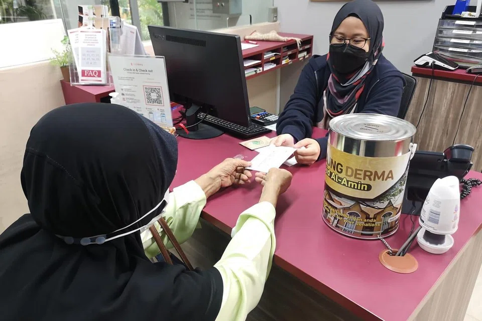 BANYAK MENYUMBANG: Seorang jemaah Muslimah Masjid Al-Amin menyerahkan cek kepada masjid sebagai sumbangan wakaf untuk projek ‘Mahar Ke Syurga’.