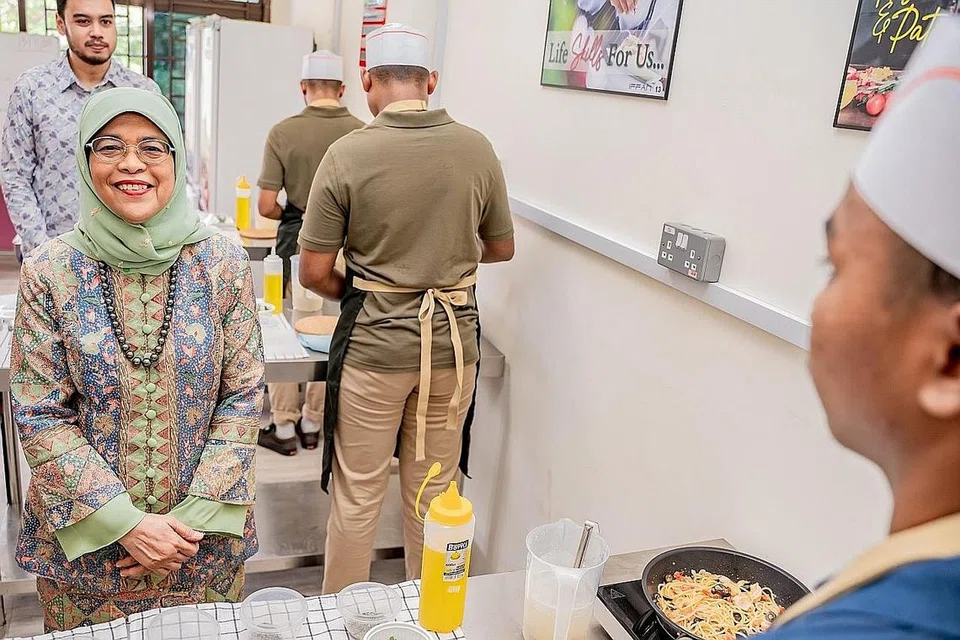 MANFAATKAN KEMUDAHAN BARU: Puan Halimah Yacob beramah-tamah bersama penghuni RKM yang sedang memasak dalam studio memasak di premis baru rumah itu semalam.