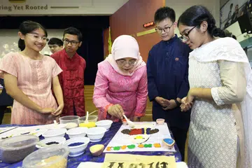 RAI KEHARMONIAN KAUM: Presiden Halimah Yacob (tiga dari kanan) bertemu guru, pelajar dan staf, serta membuat kraf Rangoli semasa mengunjungi Sekolah Menengah Northbrooks pada Khamis sempena meraikan Hari Keharmonian Kaum.