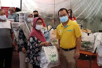 PEMBERIAN DISYUKURI: Anggota Parlimen GRC Marine Parade, Encik Seah Kian Peng (kanan) bersama antara penerima daging korban yang diagihkan. - Foto JAMIYAH SINGAPURA