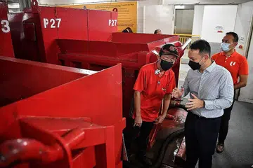 URUS SAMPAH: Encik Zaqy Mohamad (tengah) dan Encik Fahmi Aliman (kanan) berinteraksi dengan Encik Leon Lau, seorang pekerja pengisih yang bertugas di kemudahan mengisih sisa dan sampah di PLQ Mall di Paya Lebar semalam. - Foto BH oleh CHONG JUN LIANG